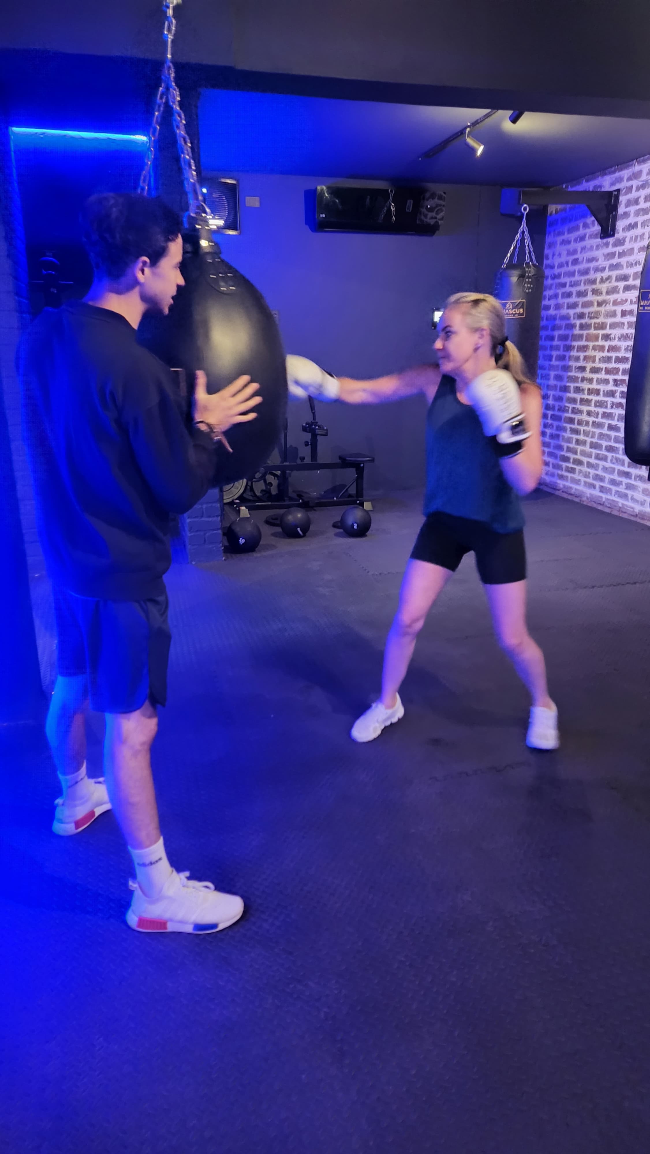 Coach holding an aqua bag while a member practises boxing technique at TENROUNDS Pretoria East