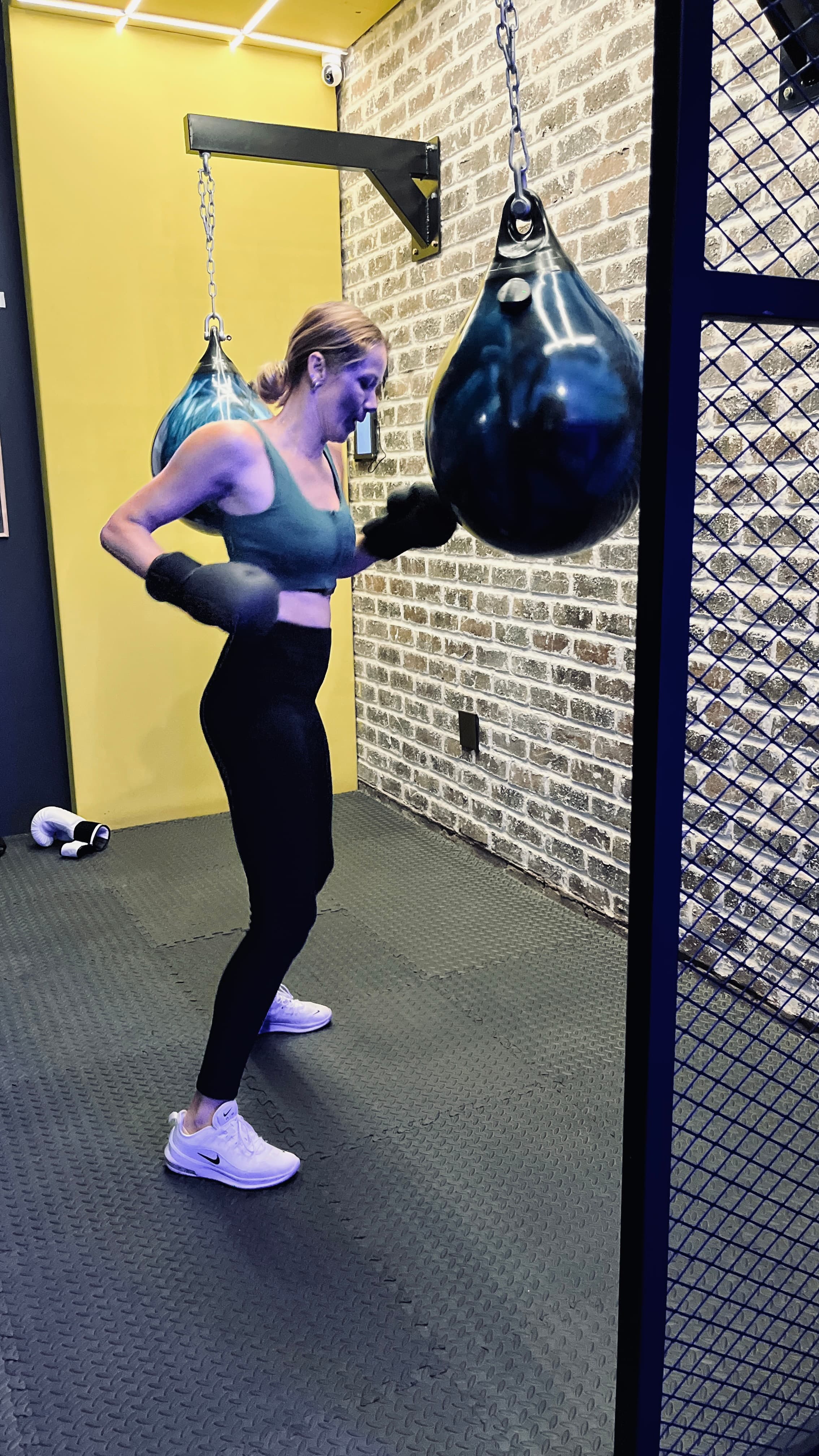 Member in a boxing guard working an aqua bag against the brick wall at TENROUNDS Garsfontein
