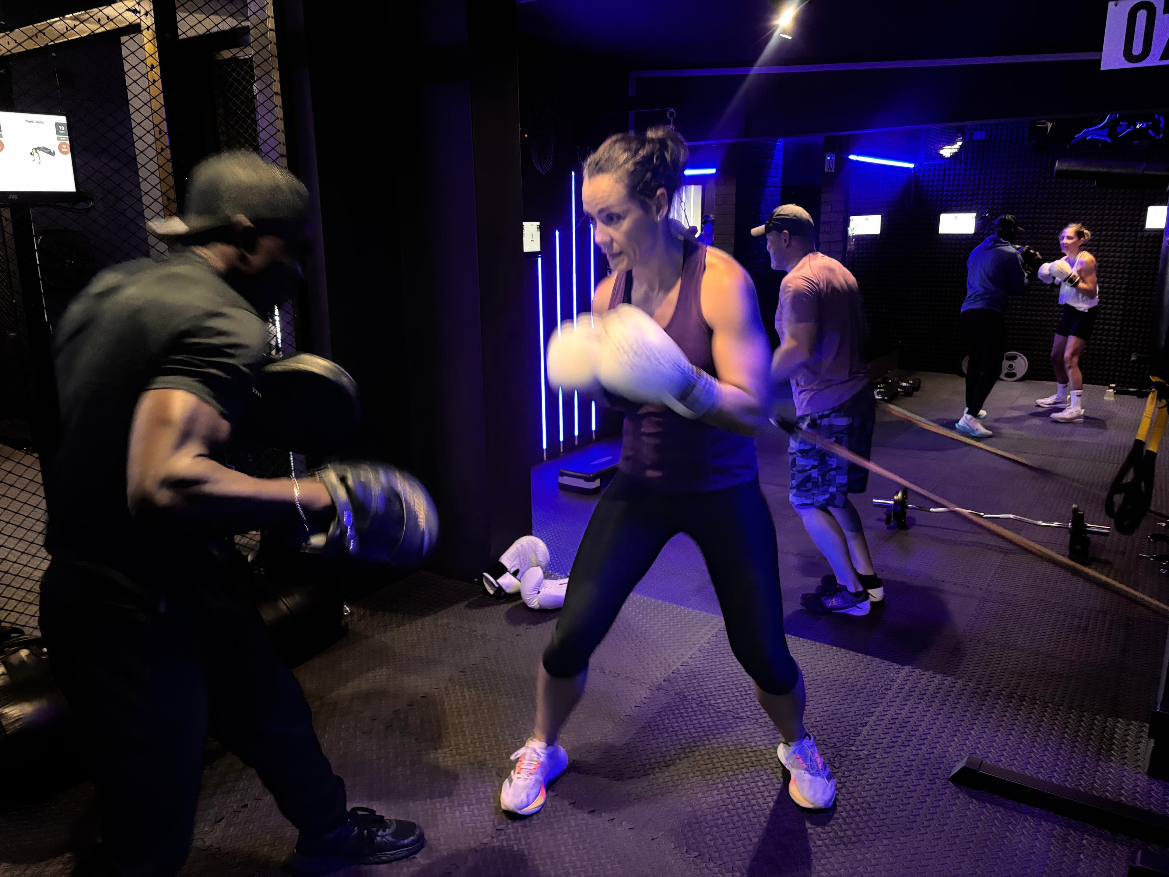 Member throwing a fast combination into a coach's focus mitts during a TENROUNDS group session in Garsfontein